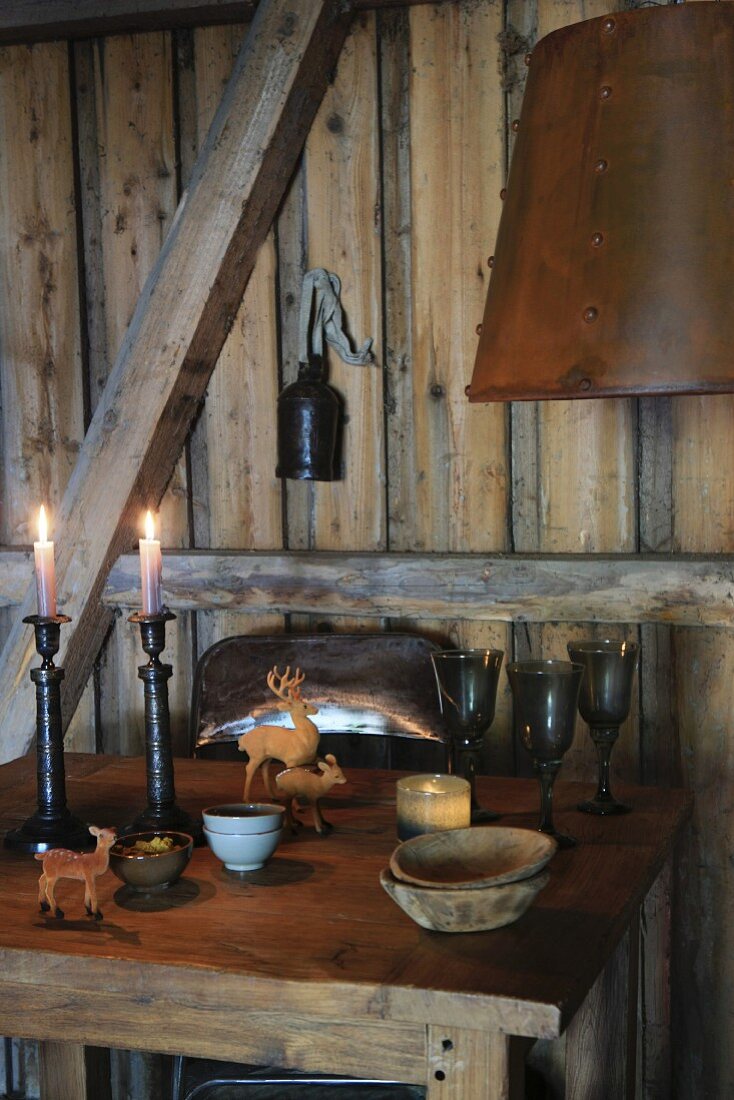 Candles and animal figurines on rustic table in wooden cabin