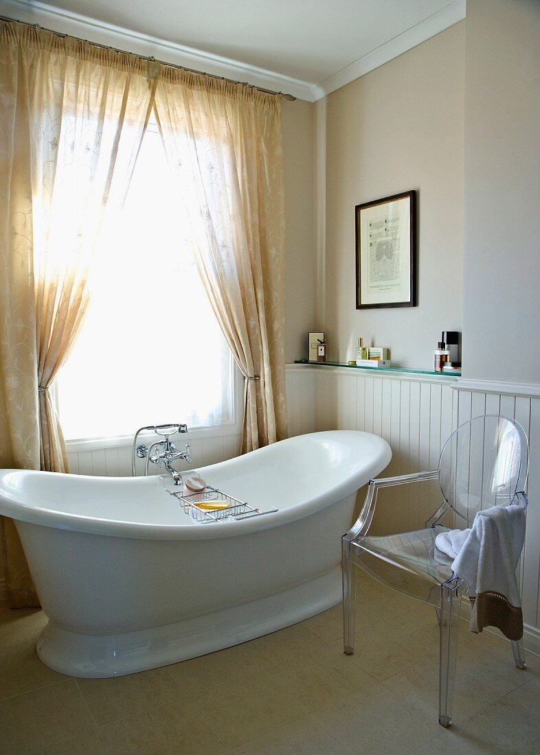 Freistehende Badewanne in traditionellem Badezimmer mit modernem Plexiglasstuhl