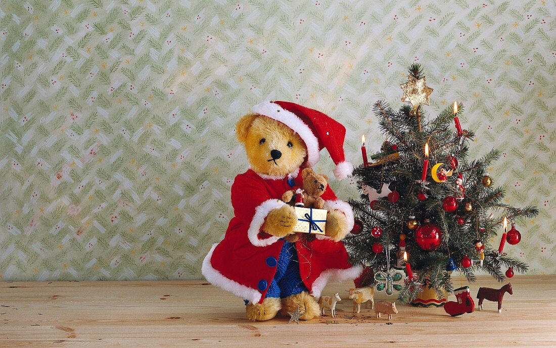 Teddybär als Weihnachtsmann und Spielzeugfiguren neben einem Weihnachtsbaum