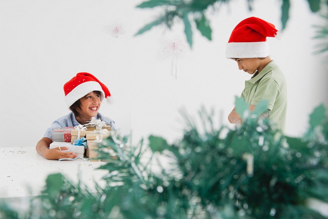 Kleiner Junge mit Weihnachtsgeschenken lächelt seinem traurigen Bruder zu