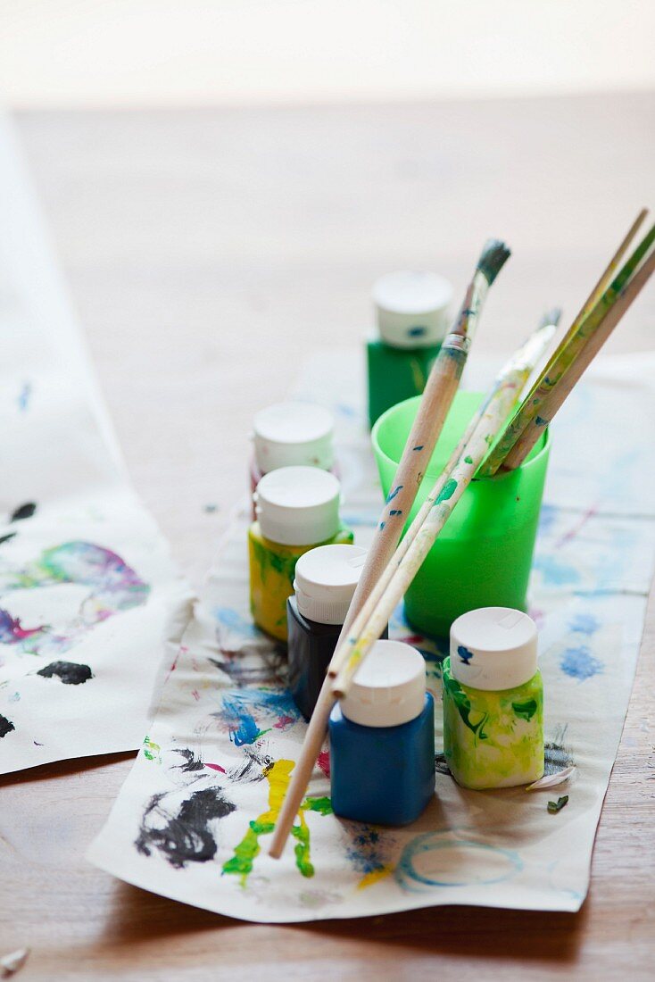 Various paints, paintbrushes and craft paper with paint tests