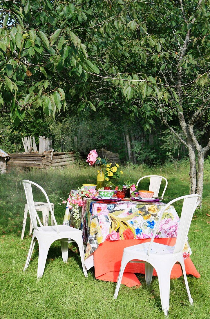 Gedeckter Tisch mit sommerlicher Tischdecke im Garten