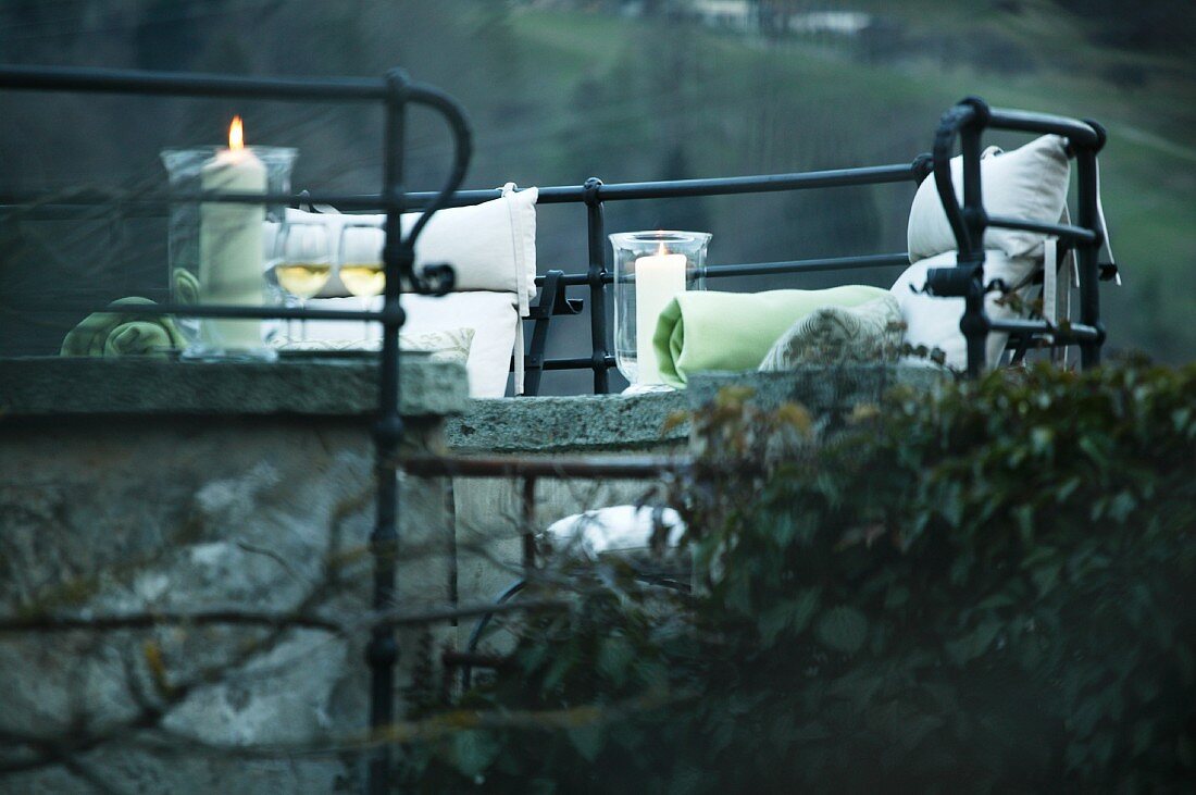 Romantischer Sitzplatz - Kissen und Kerzen auf Steinbänken umgeben von schmiedeeisernem Geländer (Schloss Schauenstein)