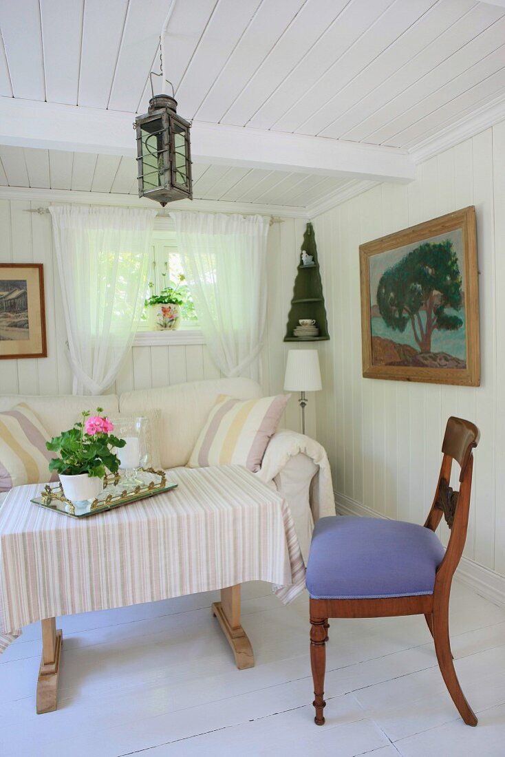 Einfaches Wohnzimmer in Weiß mit Vintagemöbeln und einem großen Ölbild mit Holzrahmen