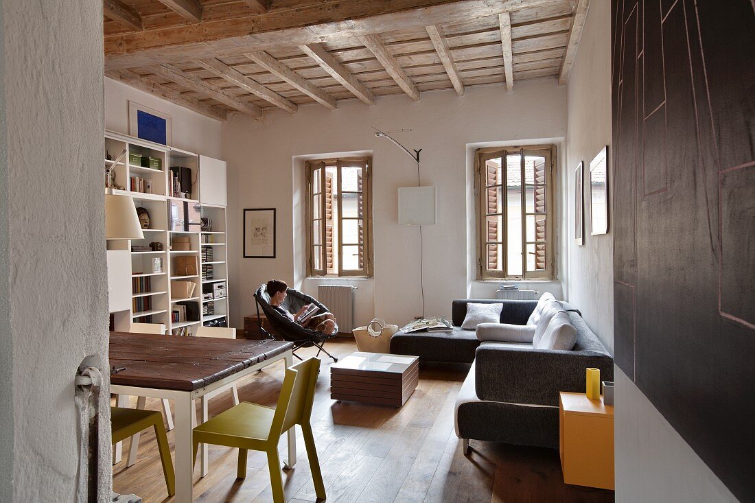 Wohnraum in ländlichem Stil mit Holzbalkendecke und verschiedenen Sitzmöbeln in verschiedenen Stilen