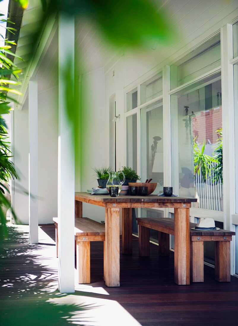 Moderne, rustikale Holztischgarnitur auf überdachter Terrasse am Wohnhaus
