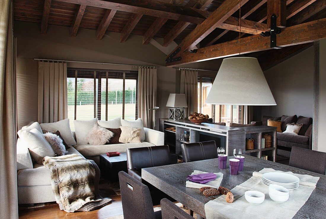 Light and dark natural palette: open living-dining room under an imposing wood beam ceiling