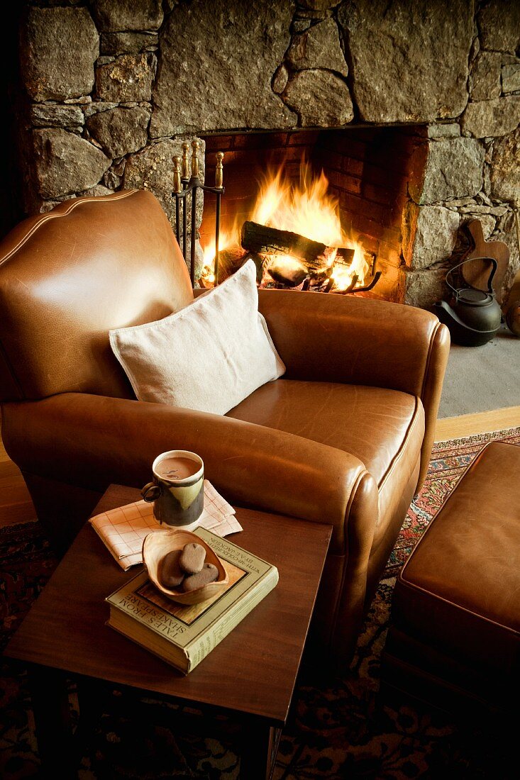Cosy spot in front of fireplace - brown leather armchair, side table and open fire