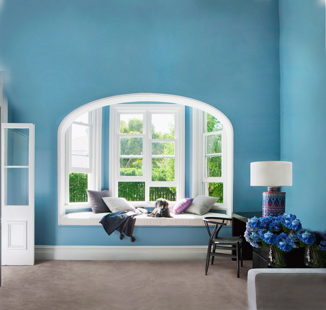 Blue, art nouveau living room with window seat and desk against wall