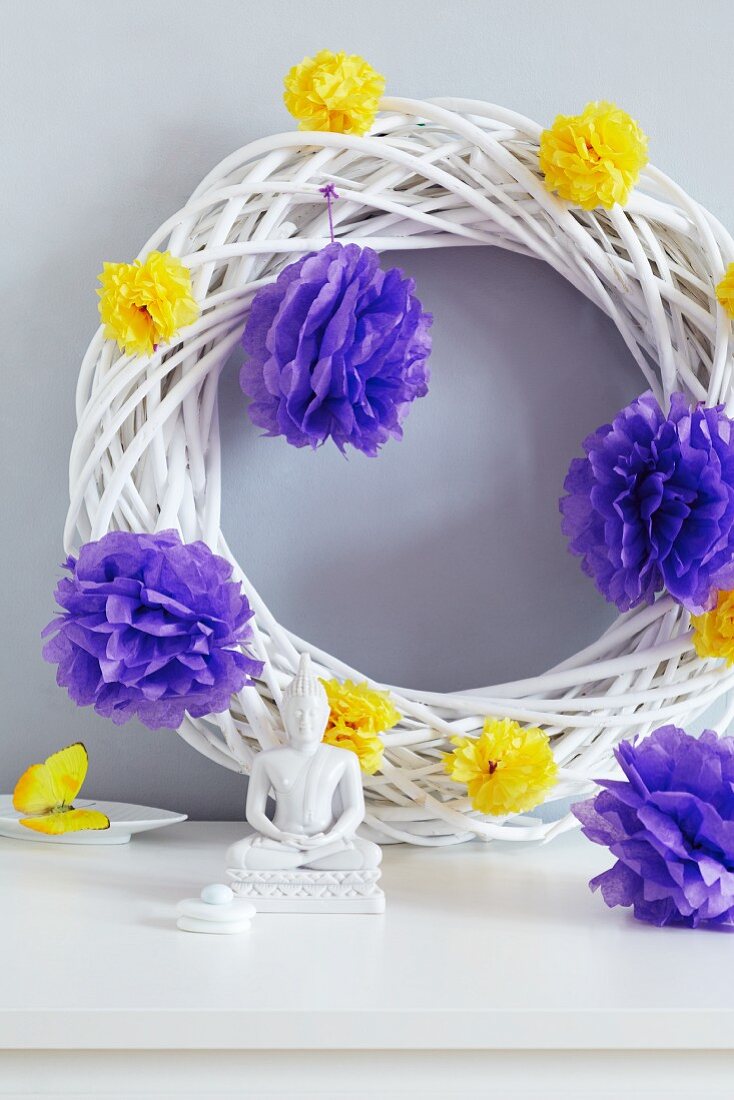 White wicker wreath decorated with tissue paper pompoms