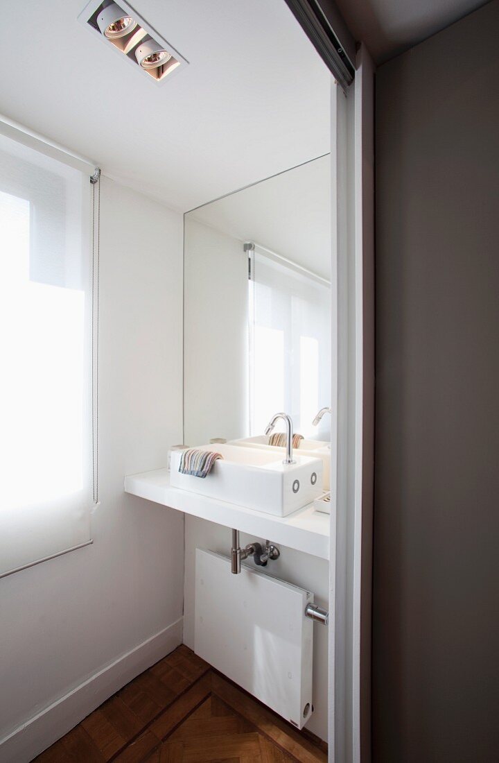 Optische Vergrößerung einer kleinen Badezimmernische durch Spiegelwand hinter modernem Waschtisch