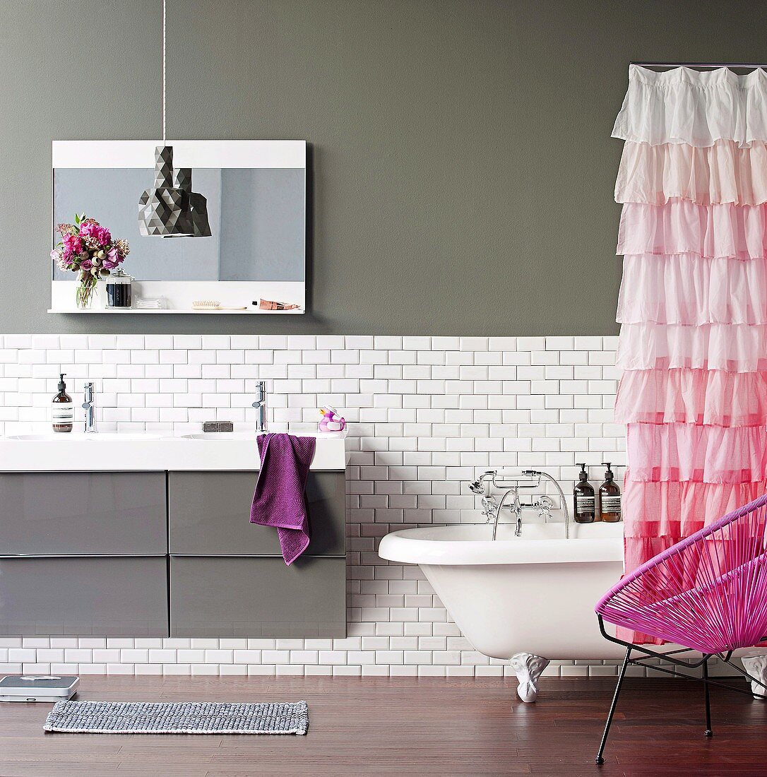 Pinkfarbener Duschvorhang mit Rüschen in einem grau-weissen Badezimmer