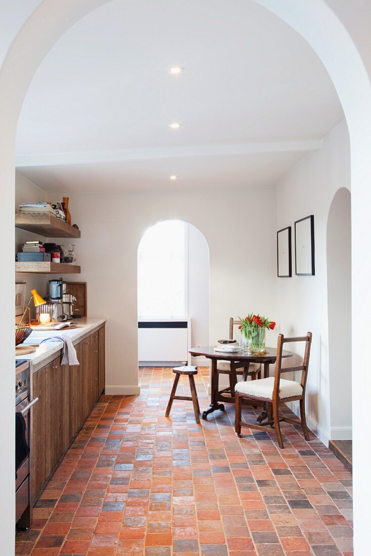 Bright kitchen with three arched doorways, terracotta tiles and wooden cupboard doors