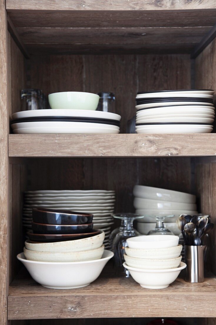 Stacked, white and brown crockery on solid wooden shelves