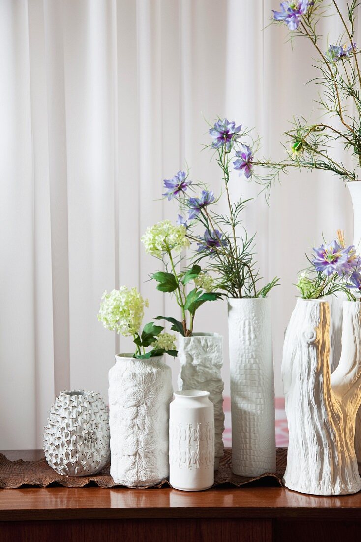 Sammlung strukturierter, weisser Porzellanvasen mit zarten Frühlingsblumen