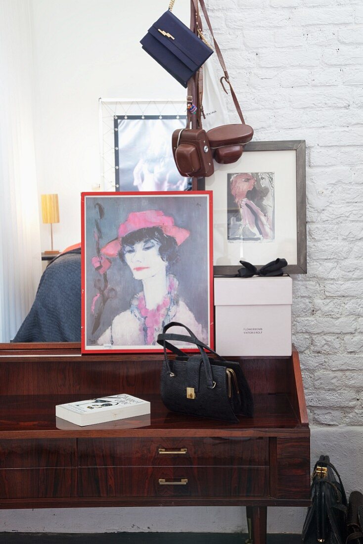 Vintage Handtasche und Frauenportrait auf 60er Jahre Schreibpult vor weisser Ziegelmauer