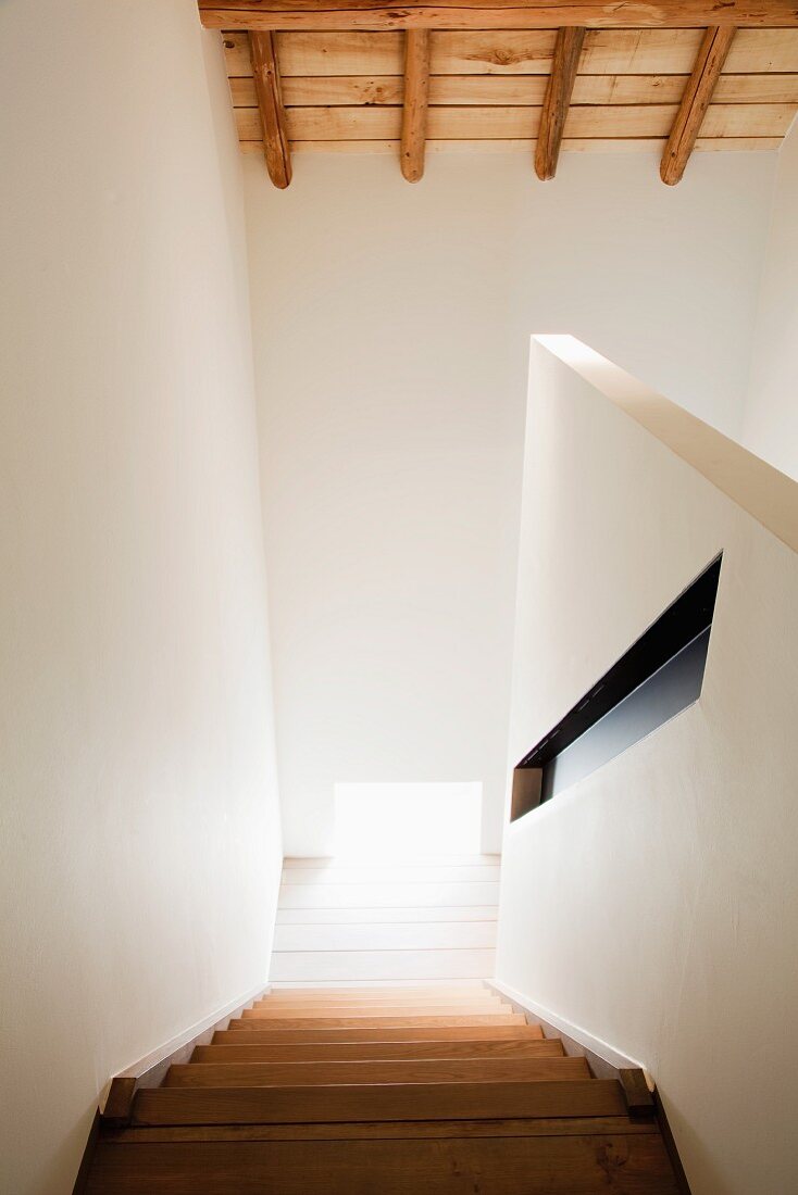 View down staircase with recessed handrail in partition wall