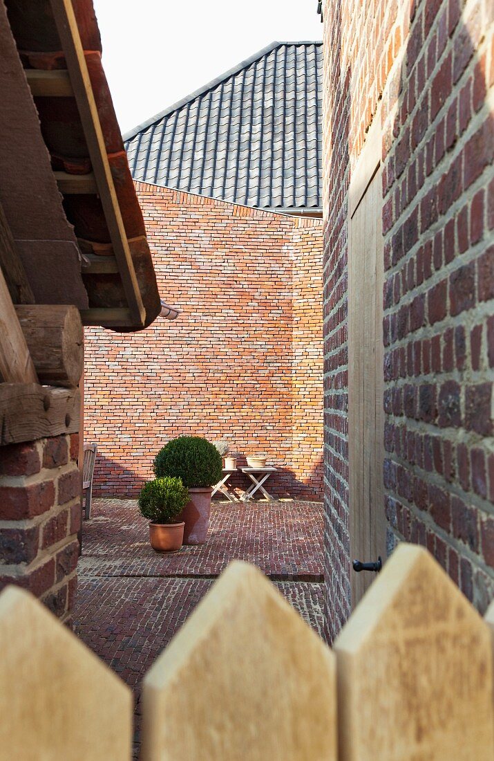 Blick über Zaun in Innenhof eines Wohnhauses in Ziegelbauweise