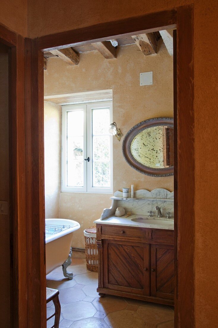 View through open door of traditional washstand with stone top in rustic bathroom