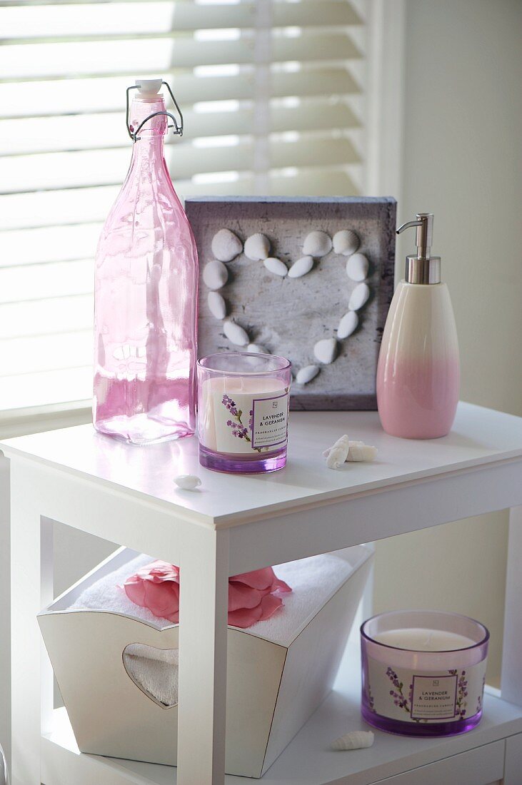 Scented candle, soap dispenser, maritime ornaments and swing-top bottle on bathroom cabinet