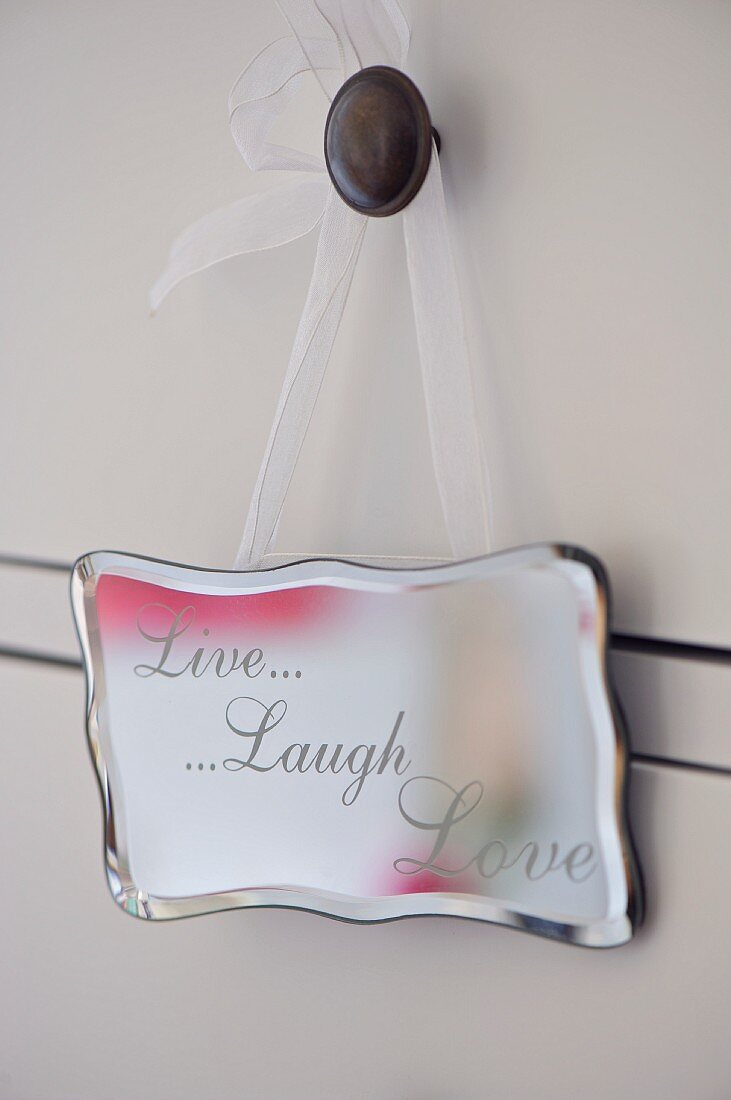 Silberschild Live Laugh Love hängt am Schubladenknauf