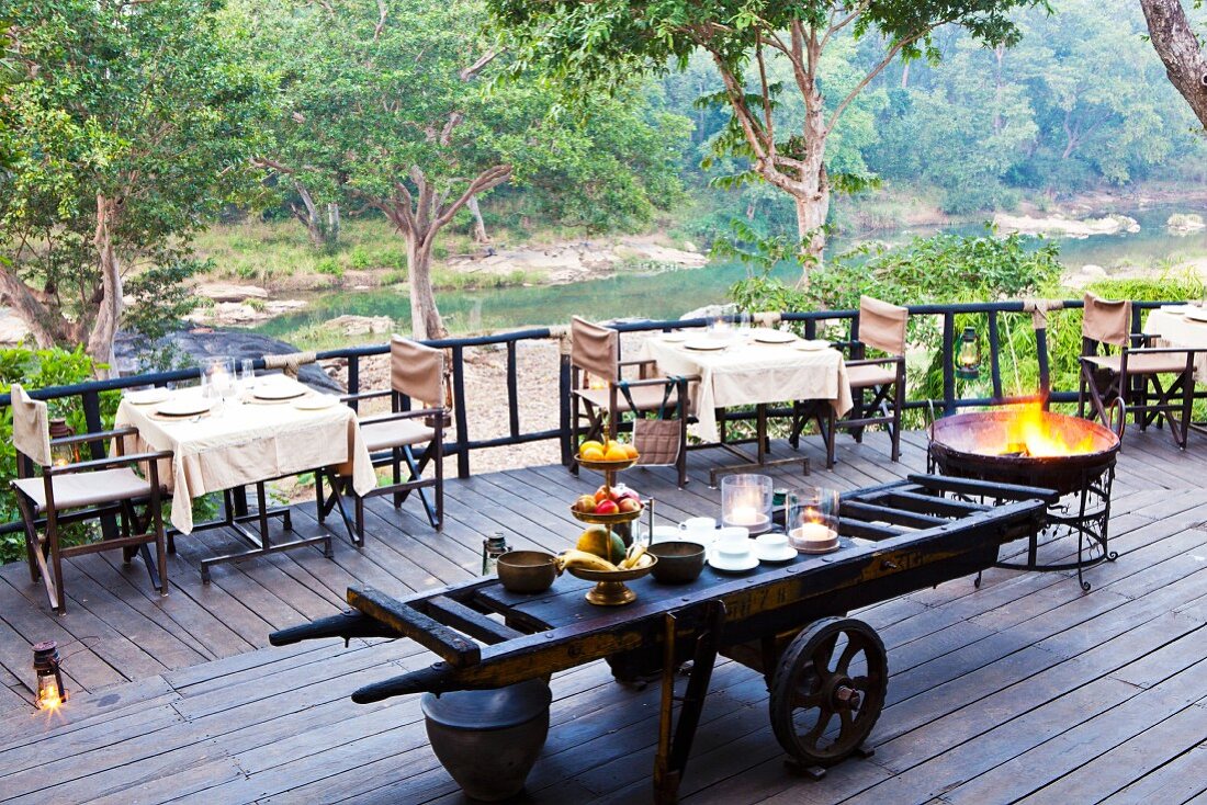Terrasse eines Restaurants mit Buffet auf rustikalem, landwirtschaftlichen Anhänger und gedeckten Tischen vor Flusslandschaft