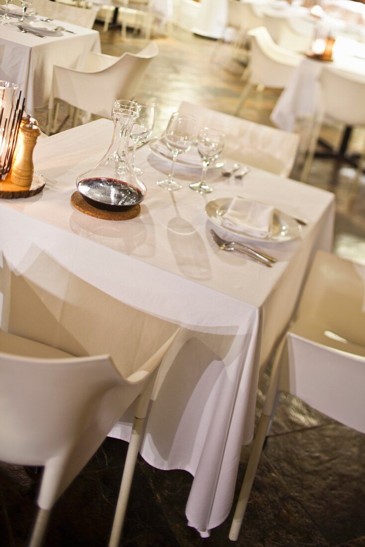 Set tables with white tablecloths and white designer chairs in dining room
