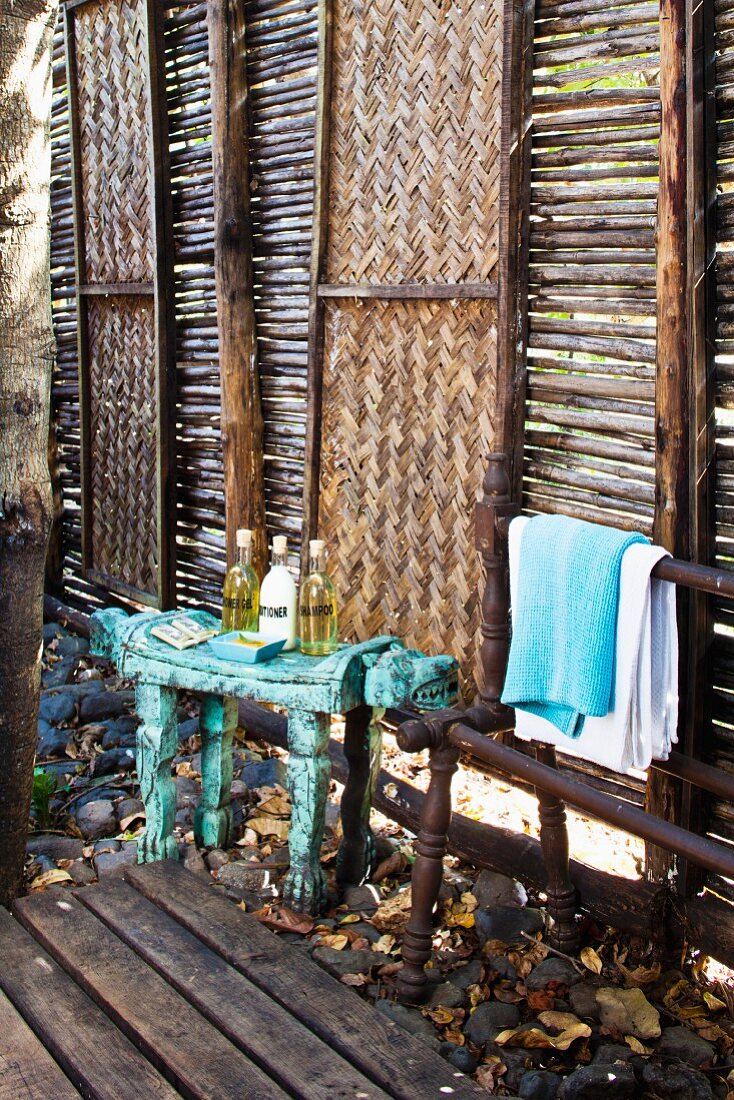 Spa toiletries on bench in front of wooden panels alternately filled with sticks and rattan