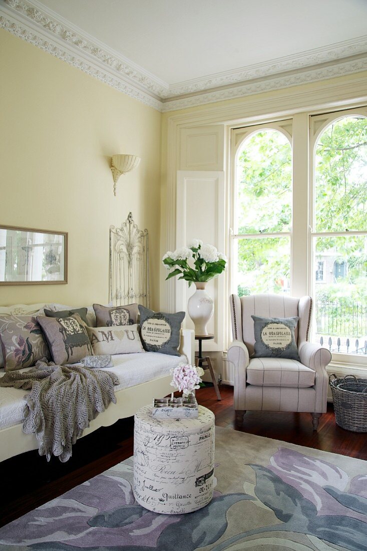 Elegante Wohnzimmerecke mit zylinderförmiger Polsterhocker, Sofa und Sessel
