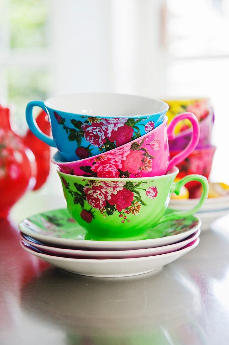 Gestapelte Tassen in kräftigen Farben mit Rosenmuster