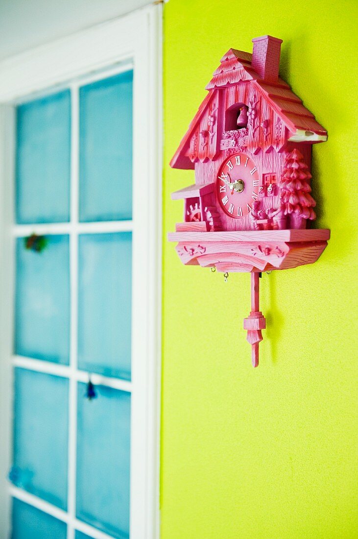 Pink cuckoo clock on spring green wall