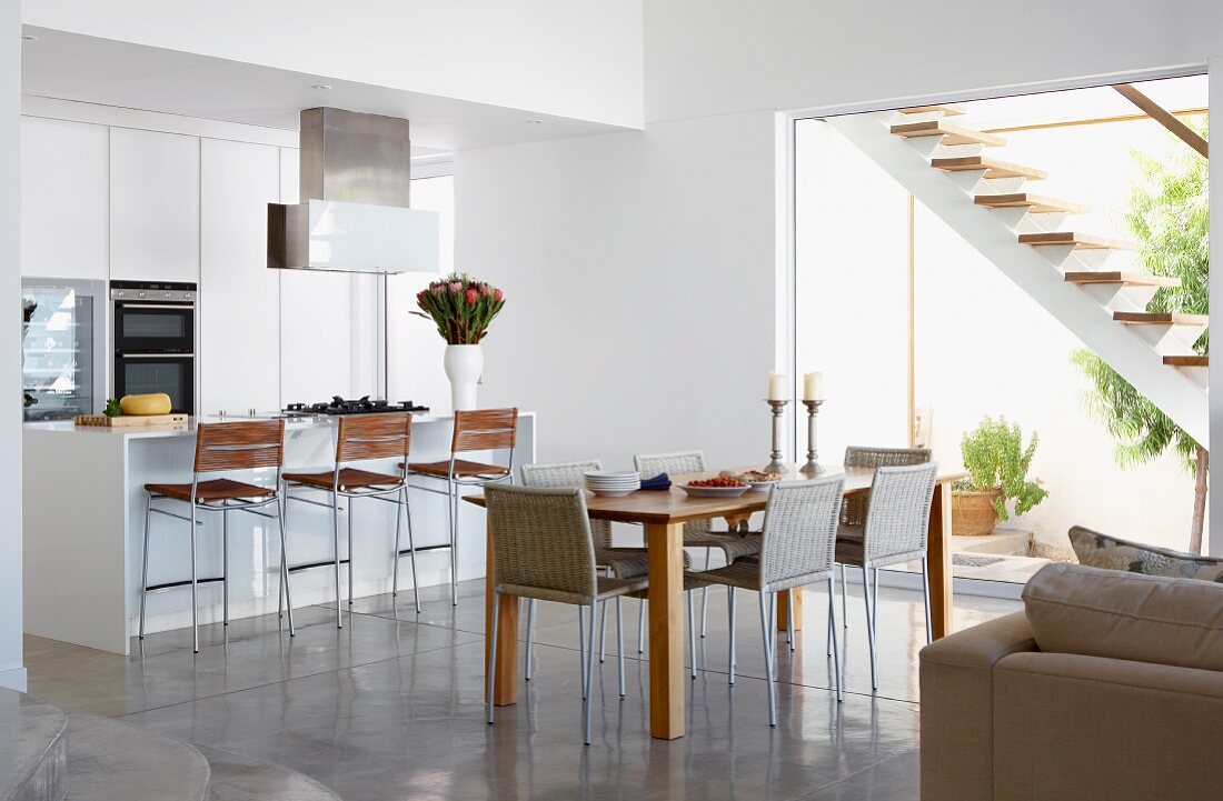 Dining area next to open-plan kitchen with floor-to-ceiling terrace window and view of external staircase