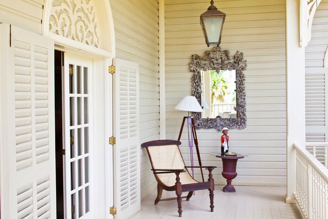 Antiker Sessel auf weisser Veranda mit offener Sprossentür und Rundbogen