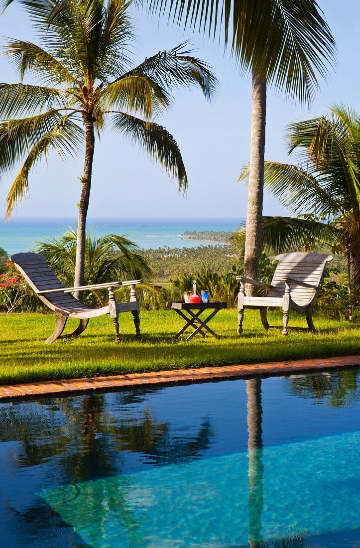 Urlaubsstimmung - Outdoormöbel mit gedecktem Beistelltisch am Pool in Palmengarten mit Meerblick