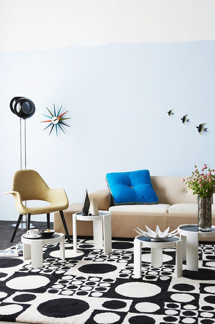 Seating area with small, round retro tables on rug with black and white, 60s-style pattern of circles