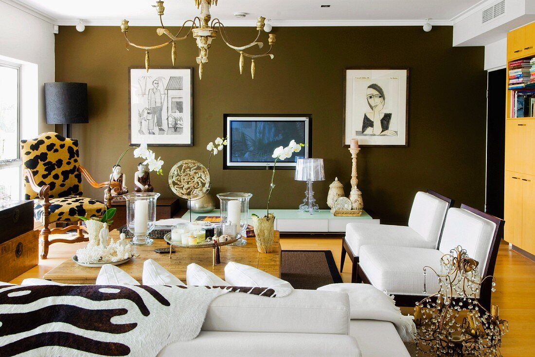 Seating area with animal print patterns and opium table in elegant living room; framed pictures on chocolate brown wall in background