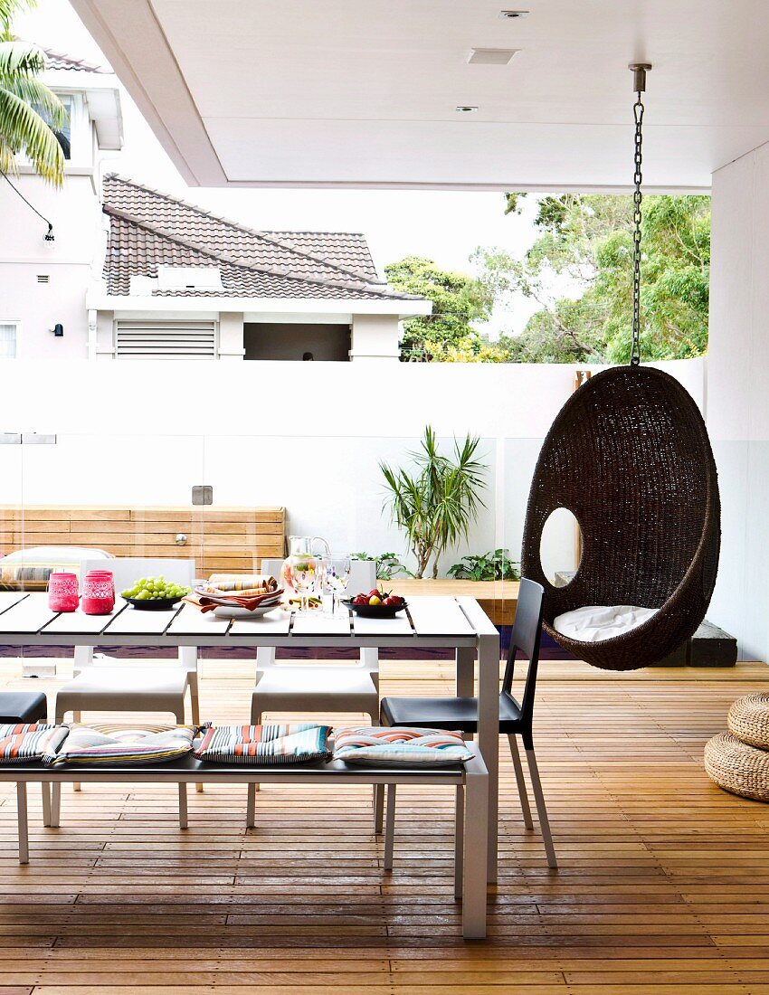 Hanging chair, table, chairs and bench on deck-style roofed terrace