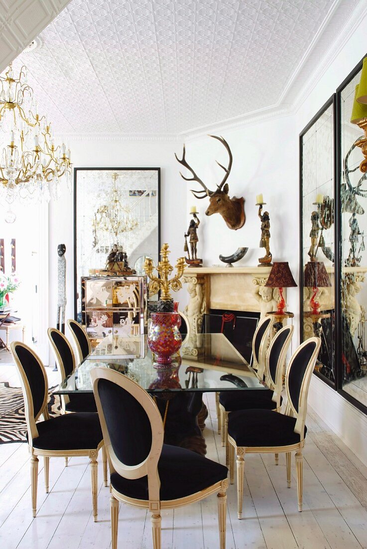Postmodern chairs around mirrored table in dining room with stag's head and large collection of ornaments