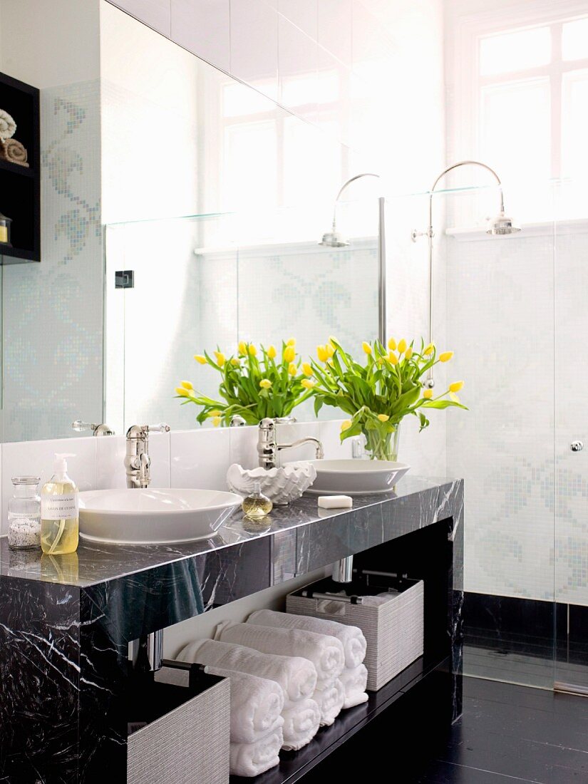 Gelber Tulpenstrauss auf Marmor Waschtisch mit Handtuchfach und Retroarmatur; bodengleiche Dusche im Hintergrund