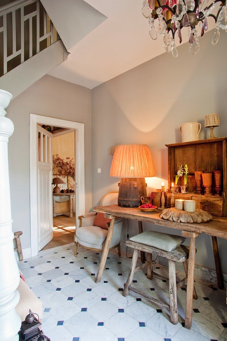 Rustic table, stools and upholstered chairs in stairwell of renovated country house