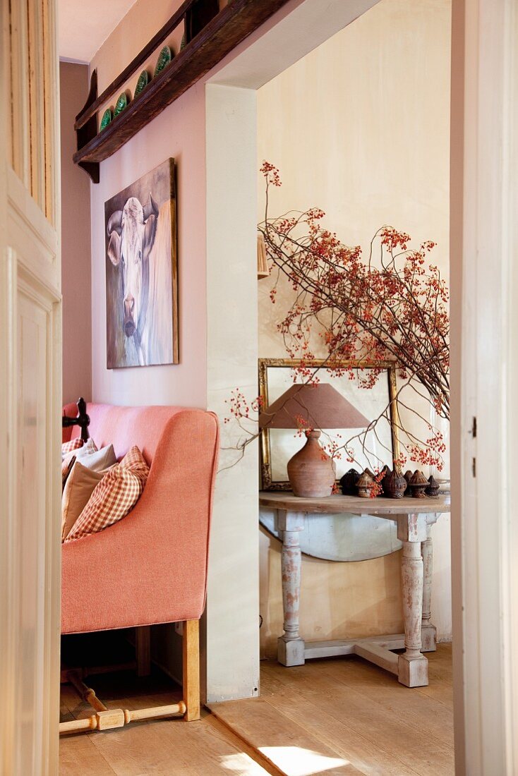 Rustic console table and salmon pink, country-house sofa in two adjoining rooms