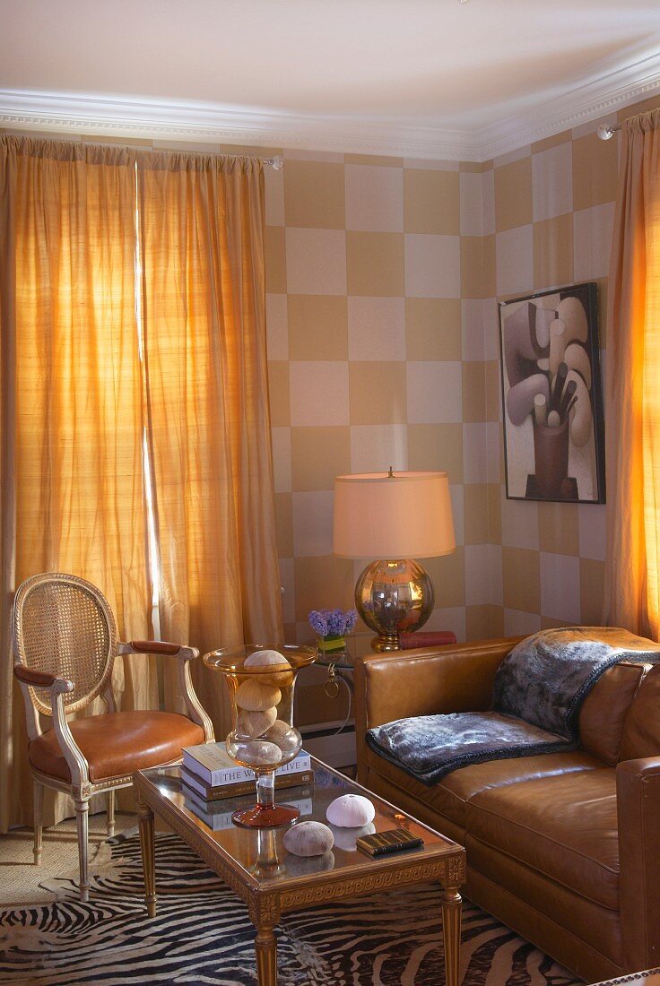 Biedermeier Couchtisch vor braunem Ledersofa und antikem Stuhl in Wohnzimmerecke mit geschlossenen Vorhängen am Fenster