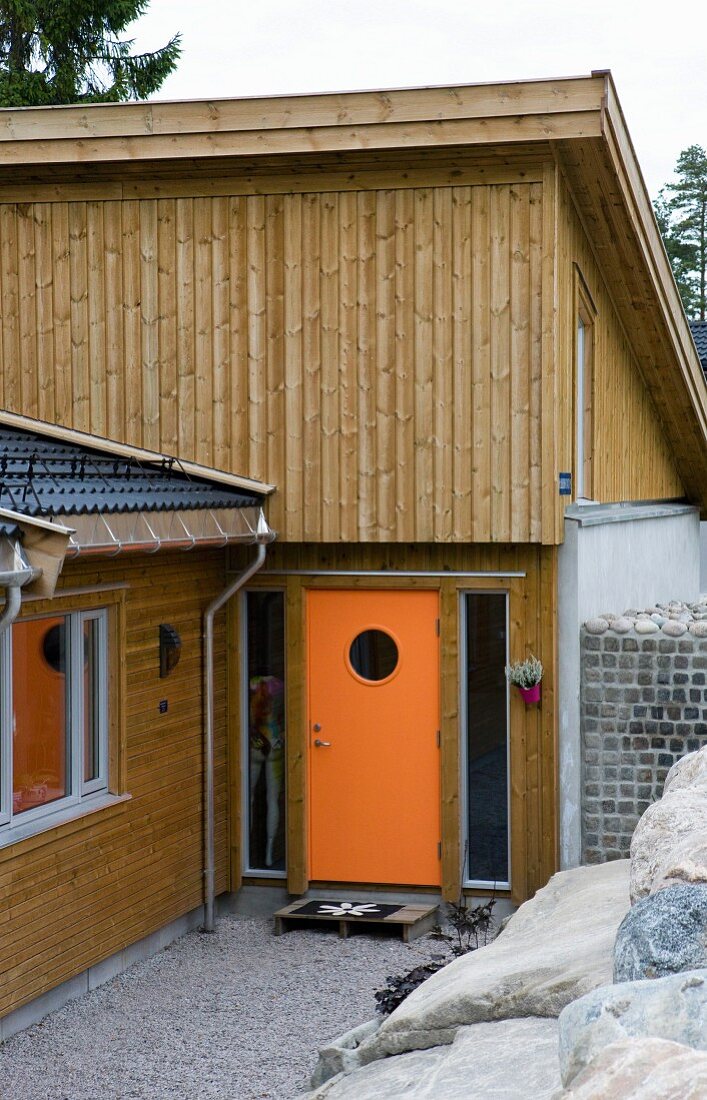 Modernes Holzhaus mit orangefarbener Hauseingangstür