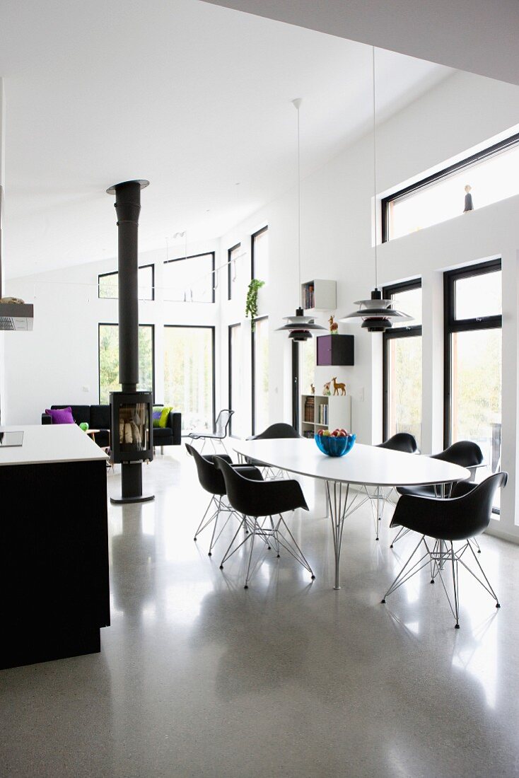 Dining area with black shell chairs around white table in open-plan, modern interior