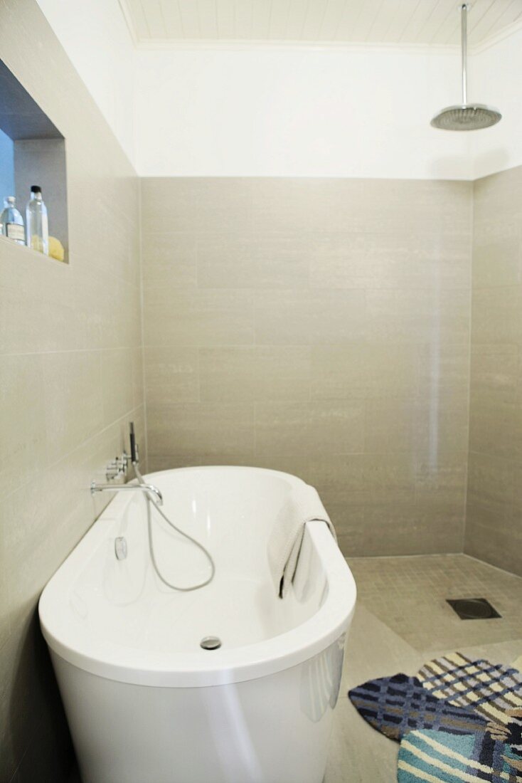 Freistehende Badewanne in gefliestem Designer-Bad mit bodenebener Dusche