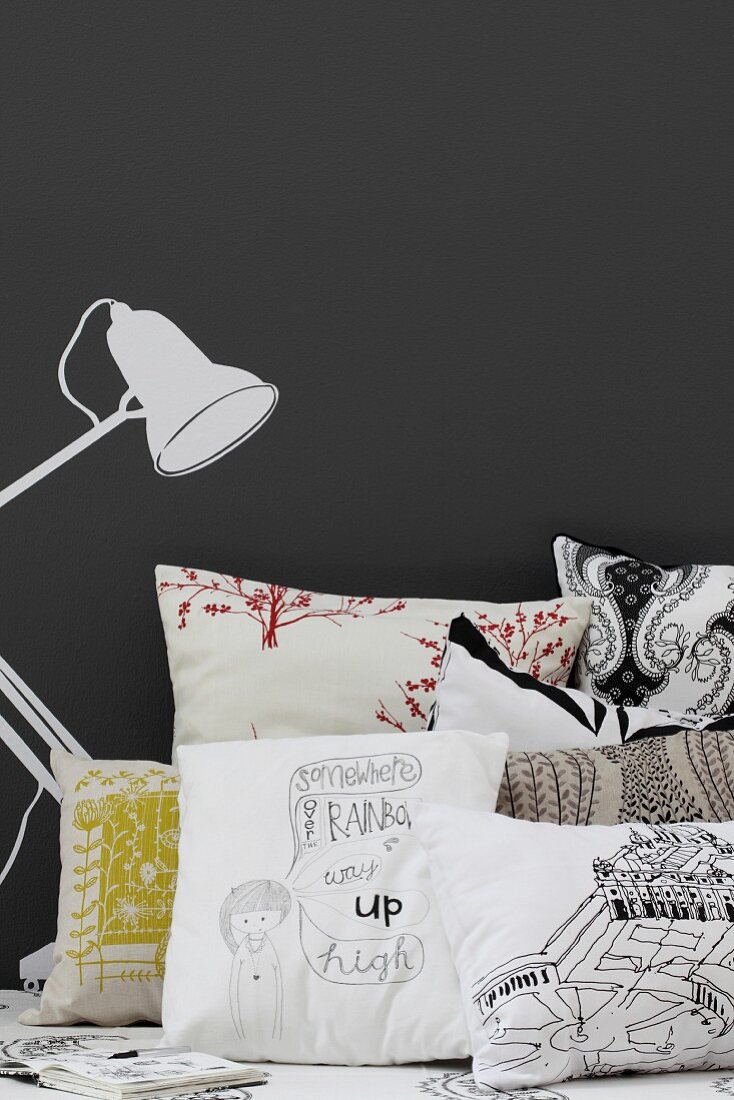 Scatter cushions next to table lamp painted on black wall
