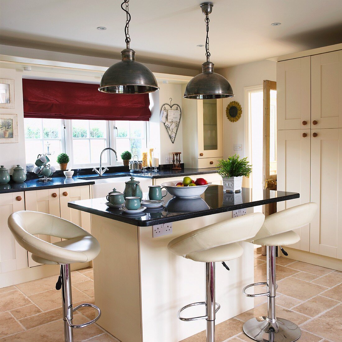 Elegant, cream, country-house kitchen with leather bar stools at breakfast bar