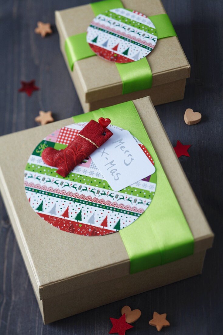 Festive gift boxes decorated with round patterned cards, green ribbons and Father Christmas boot