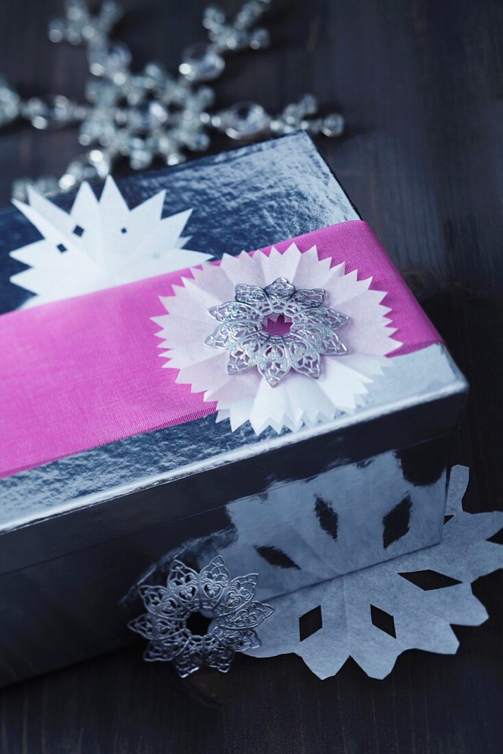 Silberne Geschenkschachtel mit weihnachtlichen Scherenschnitt-Faltsternen und ziselierten Metallsternen