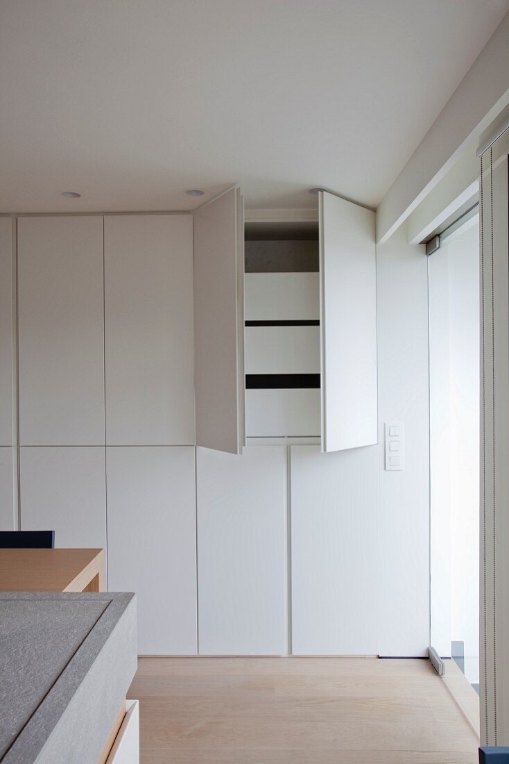 Inconspicuous fitted cupboard with open doors in kitchen